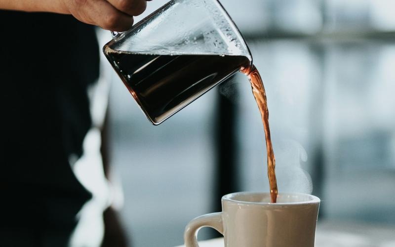 a person pouring a carafe of coffee into a cup